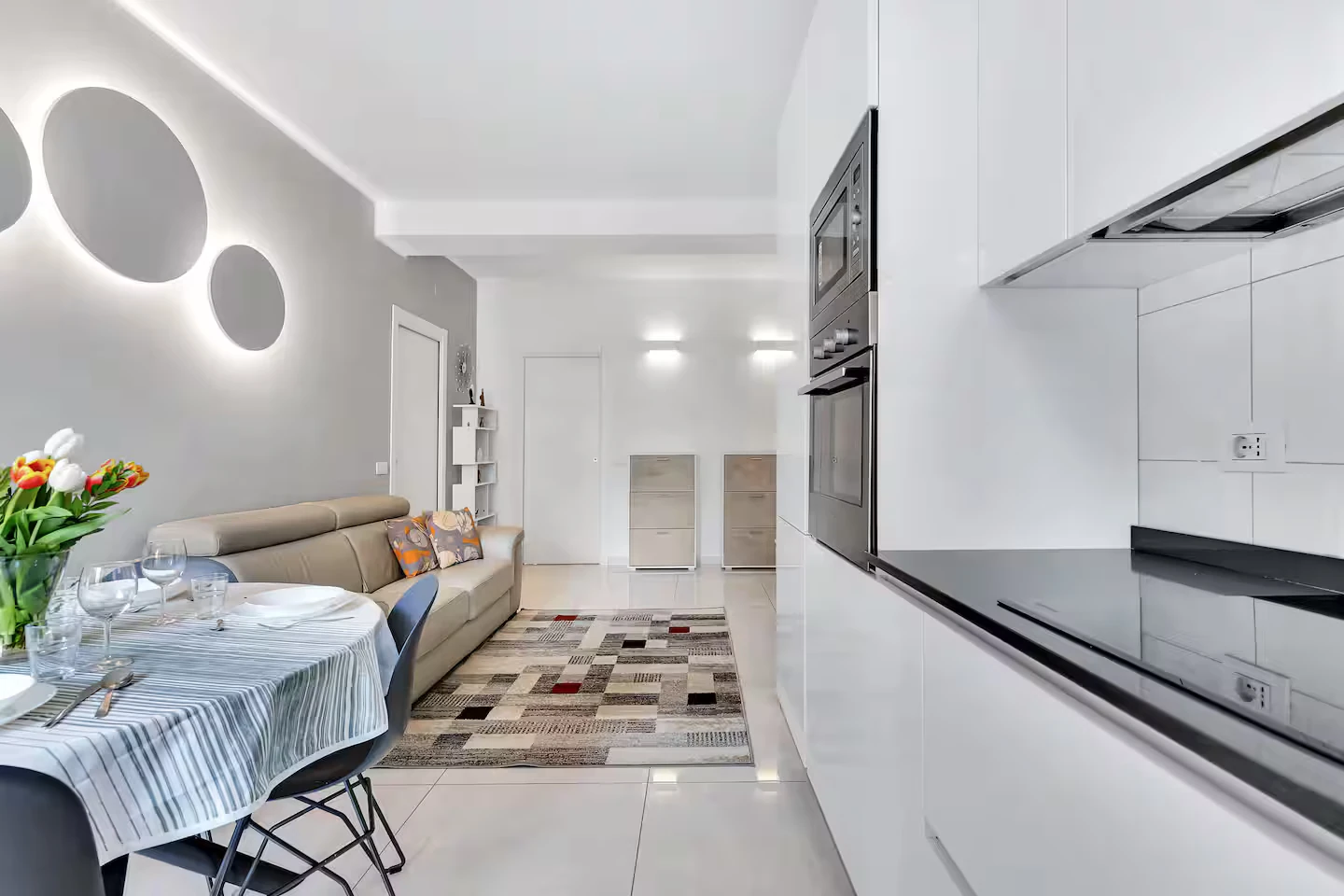 Cucina a vista sulla zona giorno, con tavolo e divano