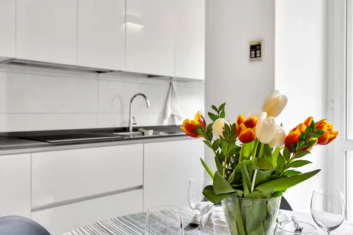 Piano della cucina e tavolo apparecchiato con un mazzo di tulipani