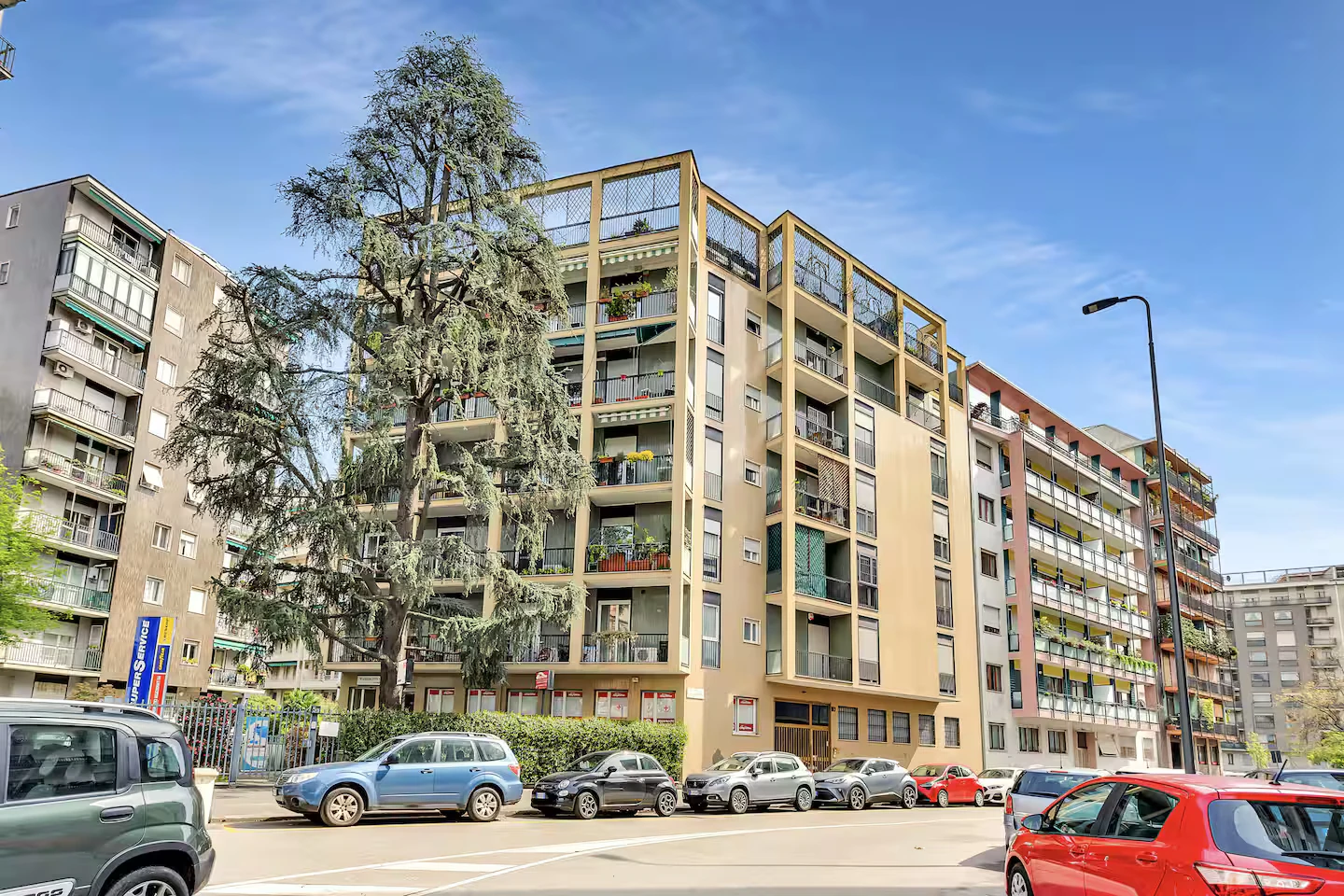 Facciata del palazzo residenziale di Alex House a Milano, tra gli alberi